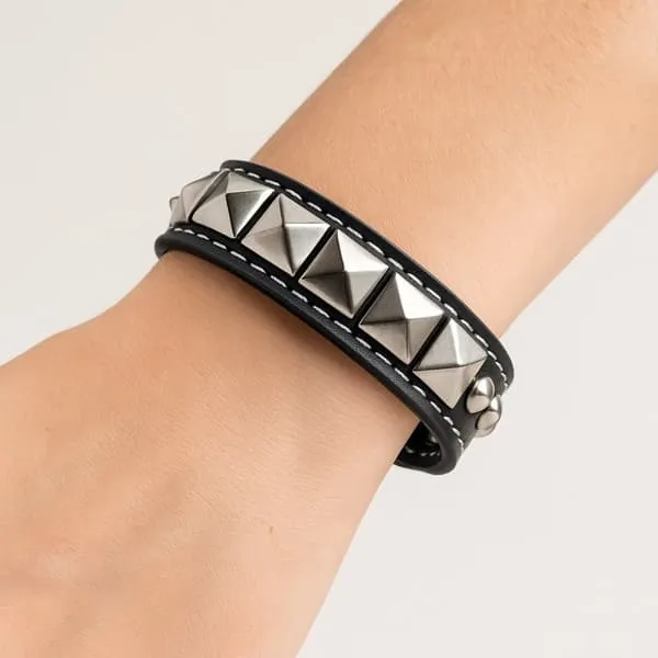Svart armbånd med runde og pyramideformede ørestikker